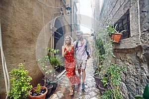 A young couple is walking around narrow streets of the old city during a vacation on the seaside. Vacation, seaside, relationship