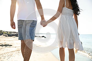 Young couple walking on beach near sea. Honeymoon trip