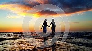 Young couple walking on the beach in the waves