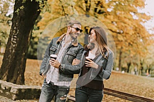 Young couple walking with coffee cups in the autumn park