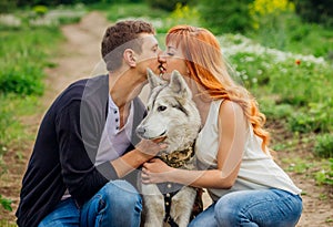 A young couple walking a dog in the park