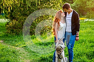 A young couple walking a dog in the park