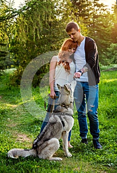 A young couple walking a dog in the park