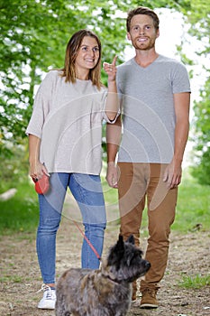 young couple walking dog in spring park