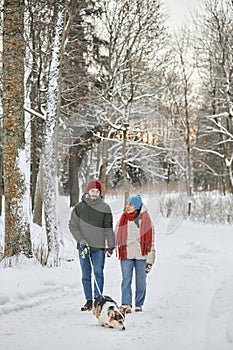 Young couple walking dog in winter forest