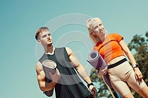 Young couple walking down the street with sports mats in their hands
