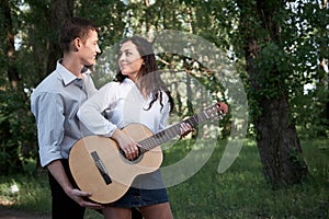 Young couple walking in the forest, playing guitar and dancing, summer nature, bright sunlight, shadows and green leaves, romantic