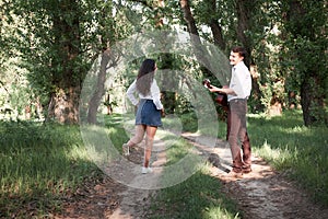 Young couple walking in the forest, playing guitar and dancing, summer nature, bright sunlight, shadows and green leaves, romantic