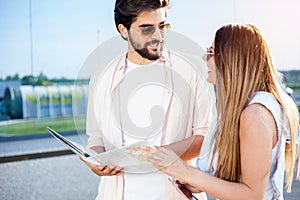 Young couple walking in front of an airport terminal building, pulling suitcases