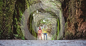 Young couple walking inside rainy forest - Hiker people having fun in to the woods - Travel, discovery, trekking, vacation and