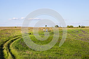 Young couple walking in the meadow, walking with dogs outdoors, beautiful setting sun