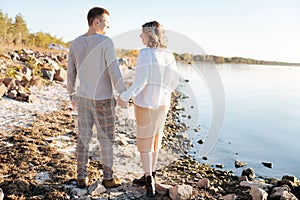 Young couple walking near the river in sunny weather