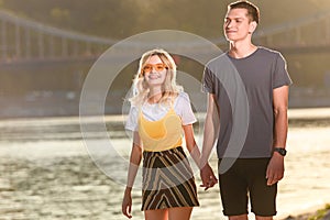 young couple walking on river beach in evening