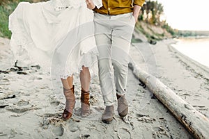 A young couple is walking on the sea coastline. Close-up image of legs. Artwork