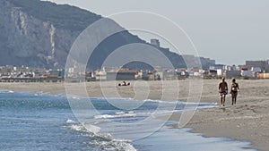 Young couple walks along the shores of the Mediterranean Sea against the background of the Rock of Gibraltar, enveloped