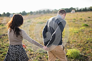 Young couple walks at sunset holding hands