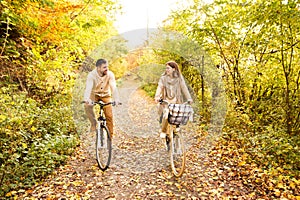Young couple in warm clothes cycling in autumn park.