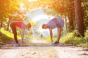 Young couple warming up and stretching on sunny day at nature