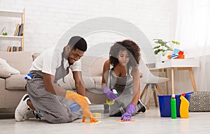 Young couple washing floor with towel and spray