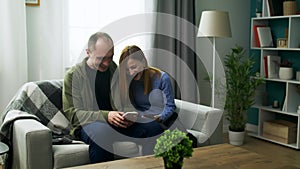 A young couple watching a fun video on a smartphone in their cozy living room