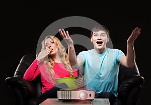 Young couple watching a movie while sitting on a sofa