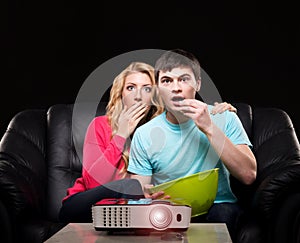 Young couple watching a movie while sitting on a sofa