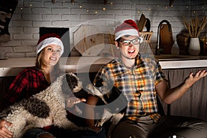 Young couple watching movies at home at christmas pointing to the screen