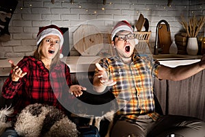 Young couple watching movies at home at christmas pointing to the screen