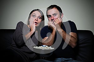 Young couple watching scary movie on tv