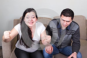 Young couple watching sport TV at home