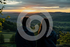 young couple watching sunrise from an undiscovered hilltop photo
