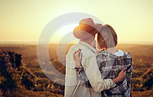 Young couple watching sunset hugging together