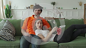Young couple watching tv with popcorn on couch