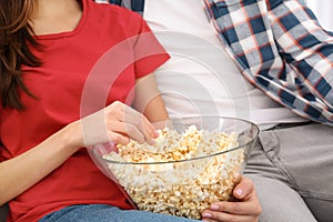 Young couple watching TV with popcorn on sofa