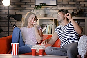 Young couple watching TV on sofa at night