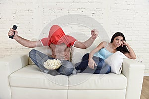 Couple watching tv sport football with man excited celebrating crazy happy goal and woman bored