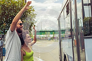 Young couple waving goodbye to their friends on the bus