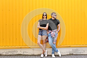 Young couple wearing black t-shirts near color wall