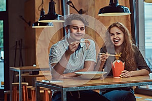 Young couple wearing casual clothes eating spicy noodles in an Asian restaurant.