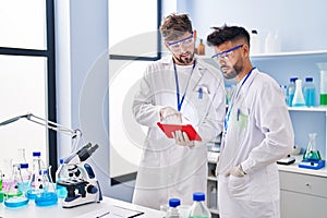 Young couple wearing scientist uniform using touchpad at laboratory