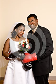 Young couple in wedding attire wearing boxing gloves