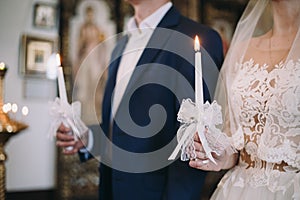 Young couple on a wedding ceremony is holding a burning candles in their hands