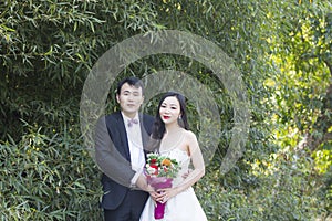 A young couple wedding photo/portrait stand by bamboo in Shanghai shui bo parkpark of water