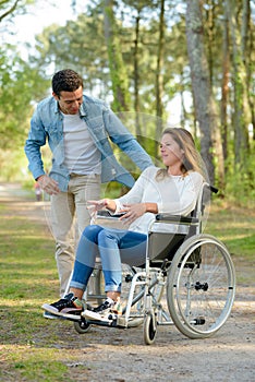 young couple in wheelchair strolling in countryside