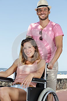 young couple in wheelchair strolling in park