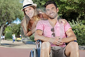 young couple in wheelchair strolling in park