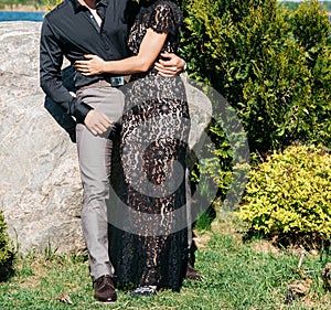 Young couple woman in a long elegant lace black dress man in trousers and shirt. love story outdoors, tenderness, hugs