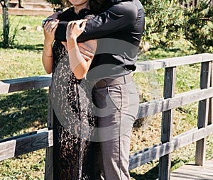 Young couple woman in a long elegant lace black dress man in trousers and shirt. love story outdoors, tenderness, hugs