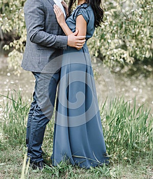 Young couple woman in a long elegant lace black dress man in trousers and shirt. love story outdoors, tenderness, hugs