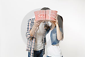 Young couple, woman and man in 3d glasses and casual clothes watching movie film on date holding buckets of popcorn